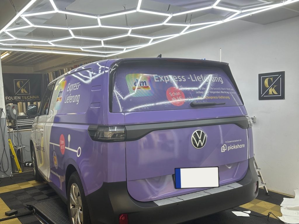 Violett vollverklebter VW ID.Buzz mit Werbebeschriftung in der Werkstatt – Fahrzeugbeschriftung von CK Folientechnik München