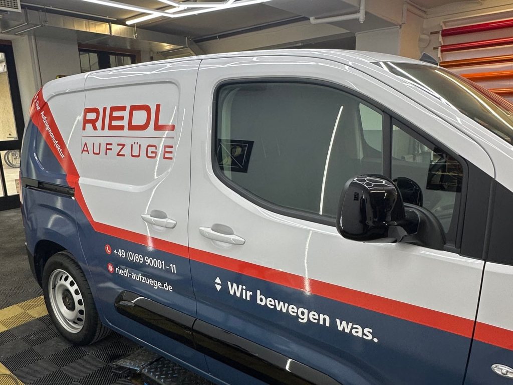 Weiß-blau beschrifteter Transporter der Firma RIEDL Aufzüge – Fahrzeugbeschriftung von CK Folientechnik München